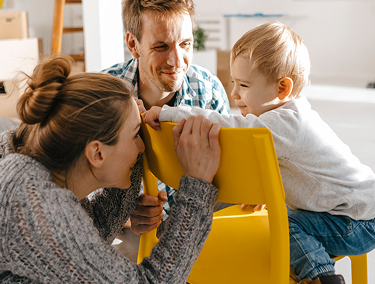 Padres jugando con su hijo pequeño en el interior de su hogar.