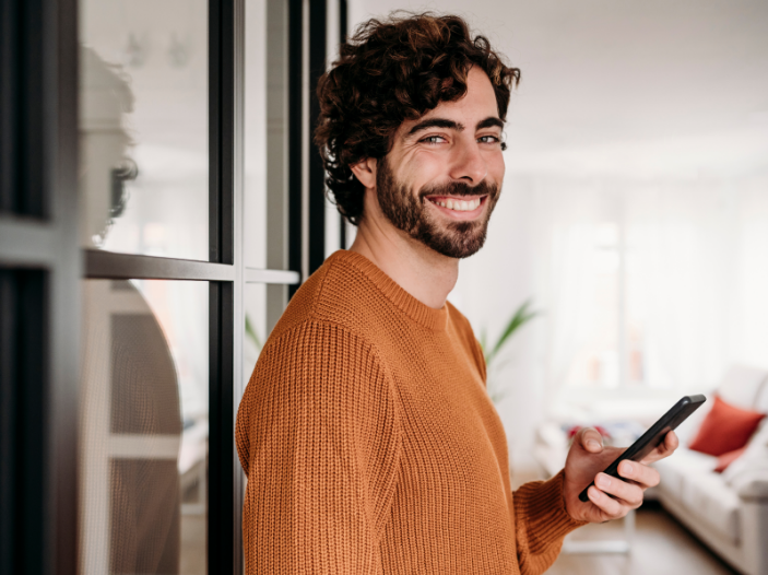 Hombre sonriendo con un celular en la mano