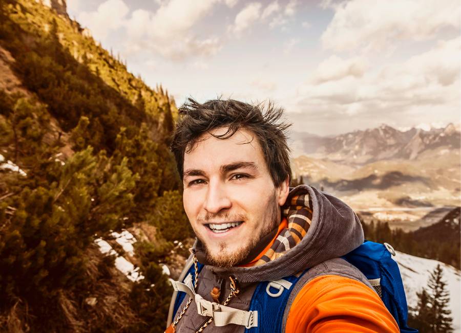 Turista tomándose una selfie con un paisaje de fondo.